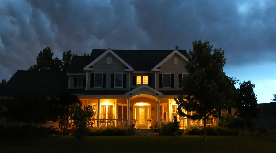 storm clouds above a house with its porch lights on